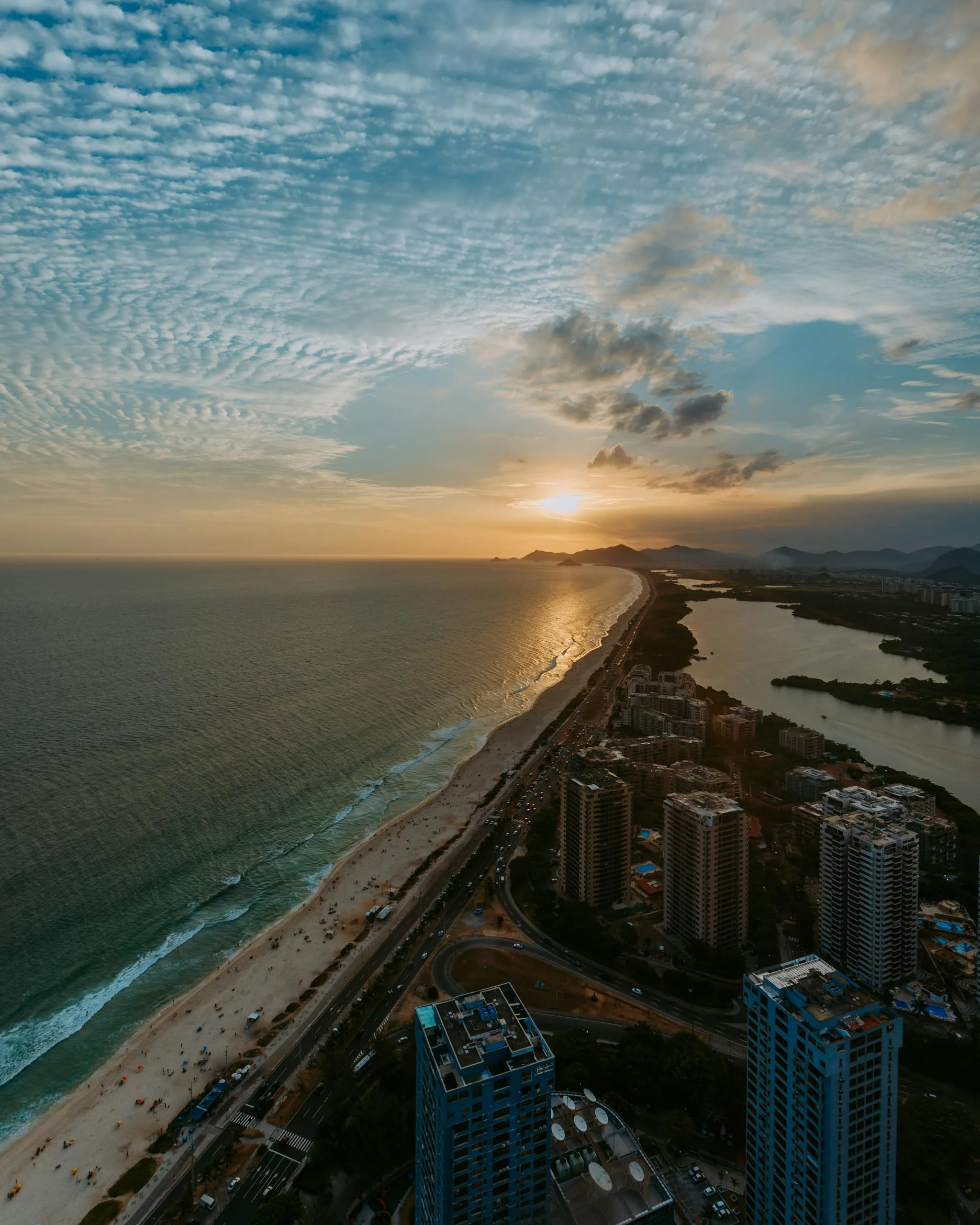 A stunning aerial view of Rio de Janeiro's coastline during a vibrant sunset, highlighting the city's skyline and natural beauty.