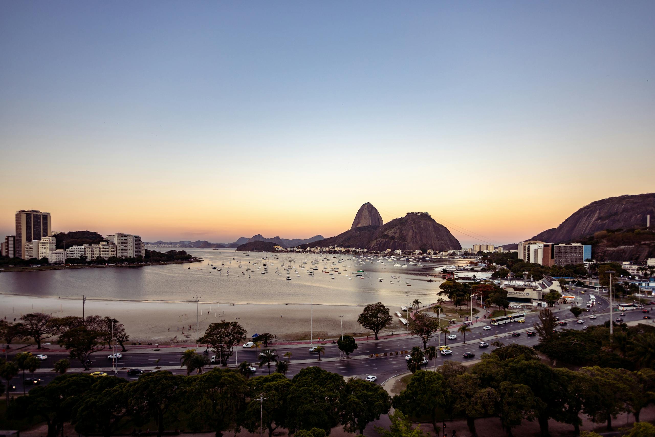 A breathtaking aerial view of Botafogo Beach, Rio de Janeiro, with Sugarloaf Mountain at sunset.