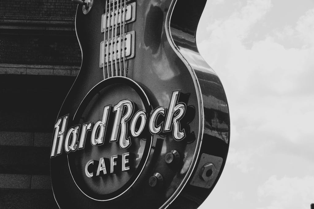 Black and white photo of the Hard Rock Café guitar-shaped sign against a cloudy sky.