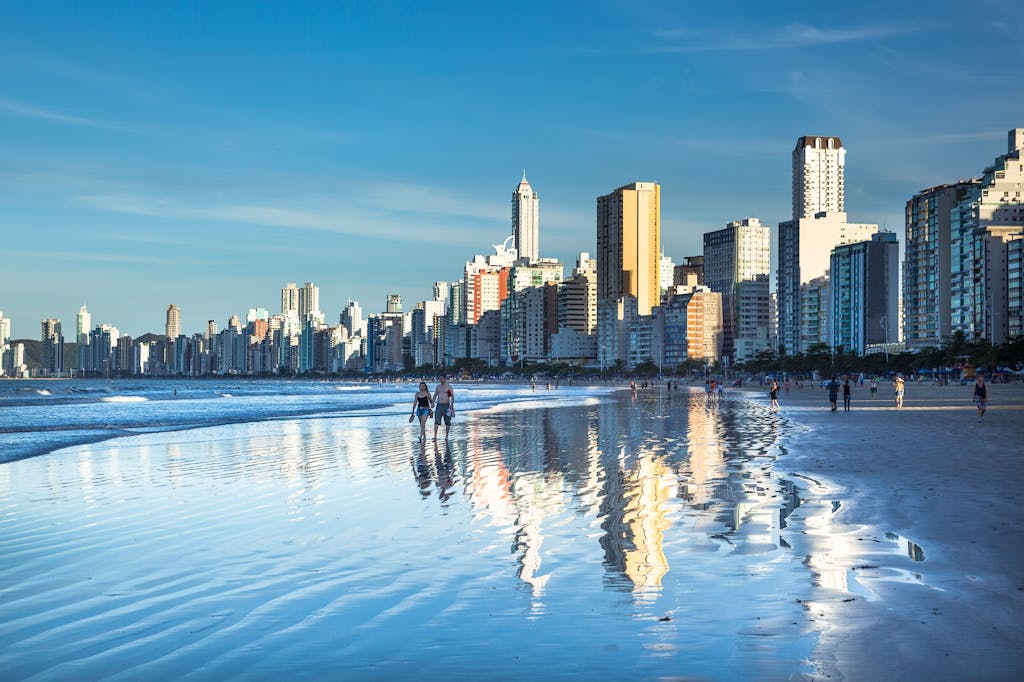Stunning view of Balneário Camboriú's modern skyline reflecting on the beach at daytime.